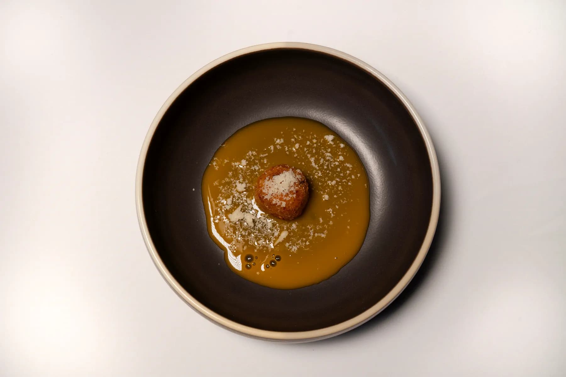Croqueta sobre crema de calabaza en cuenco de barro