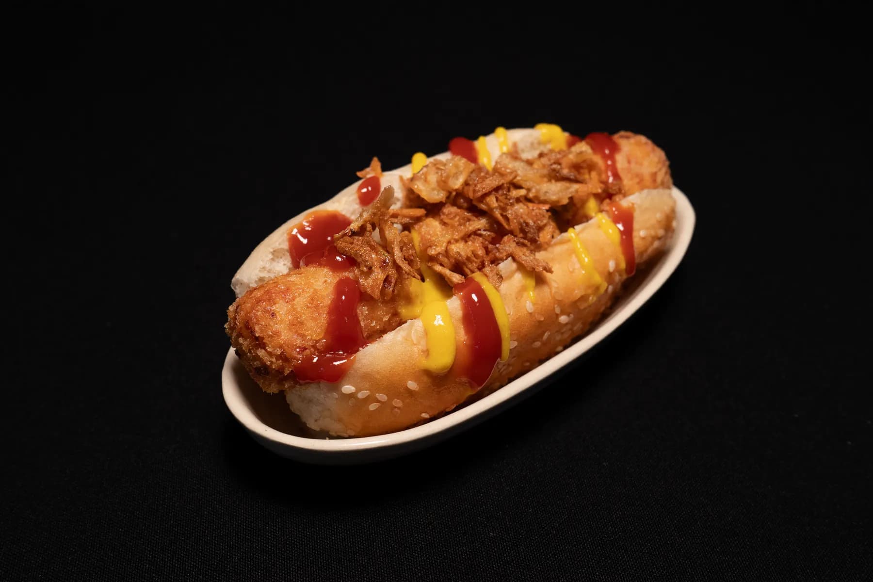 Croqueta servida en pan de perrito con salsas